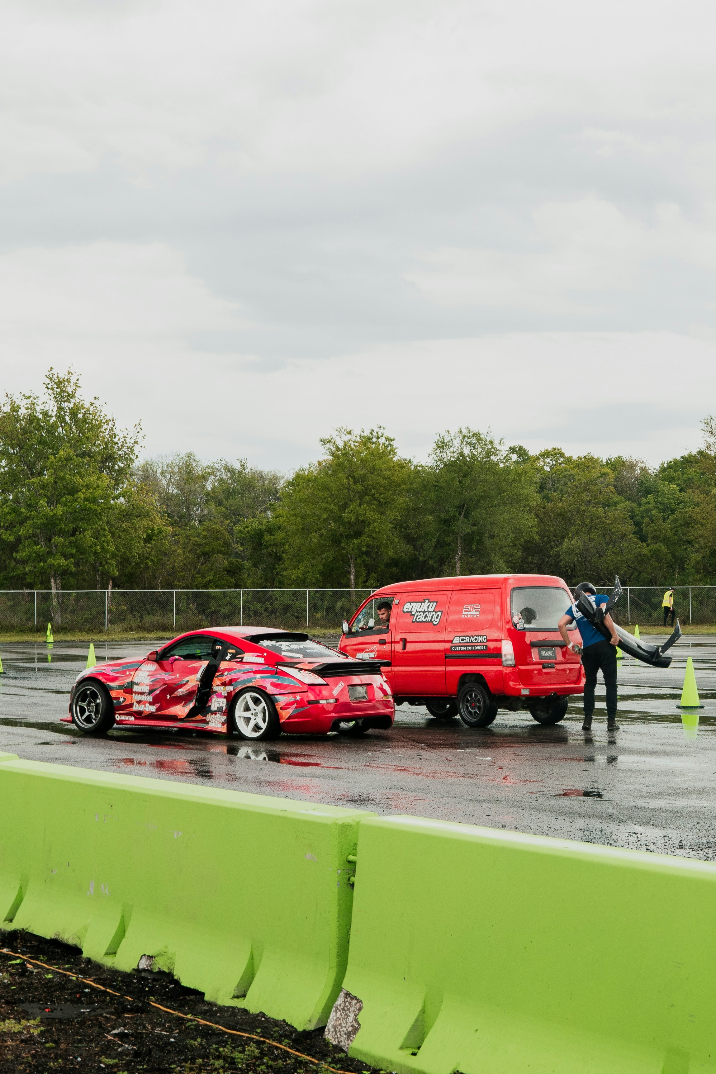 a red truck towing a red car on a wet parking lot