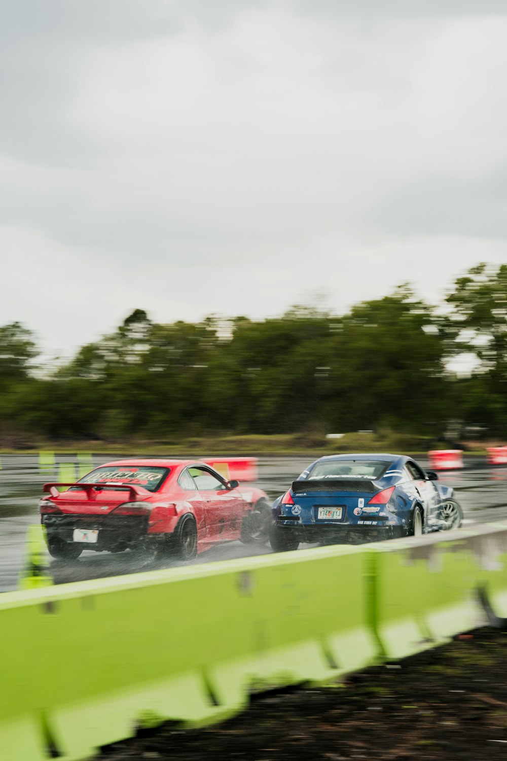 a couple of cars driving down a wet track
