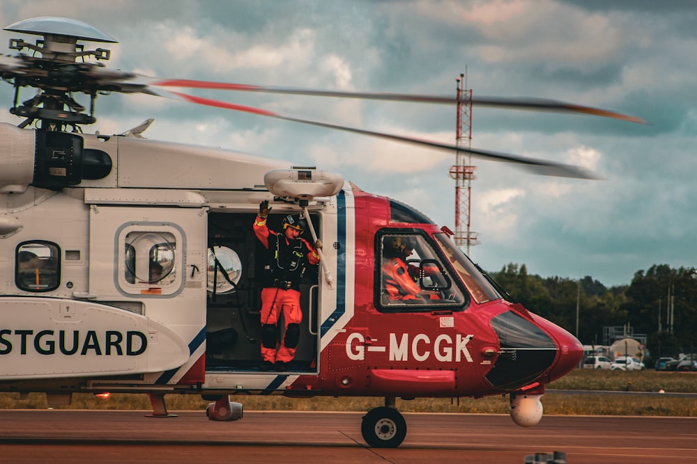 a red and white helicopter sitting on top of an airport tarmac