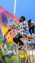 Close-up of students painting a large, colorful mural on a school wall.