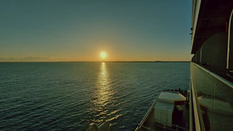 A cozy cruise ship deck overlooking calm ocean waters during golden hour.
