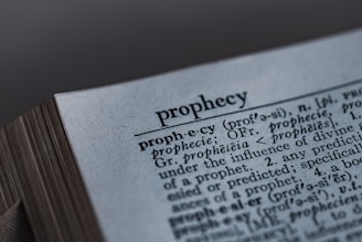 A close-up image of a dictionary page, focusing on the word 'prophecy' along with its pronunciation guide and definitions. The text includes etymological information, indicating its origins from Latin and Greek.