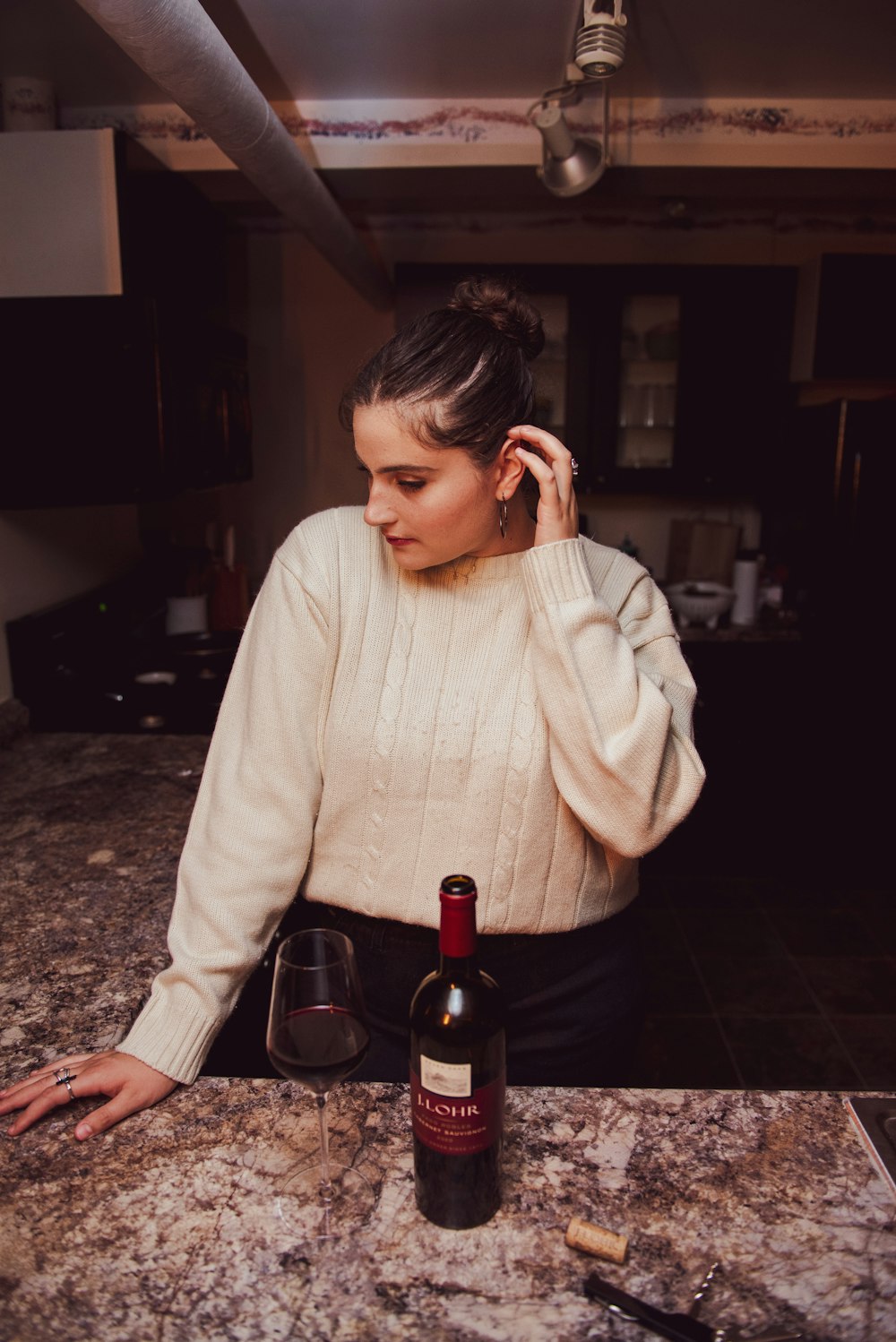 a woman sitting at a table with a bottle of wine