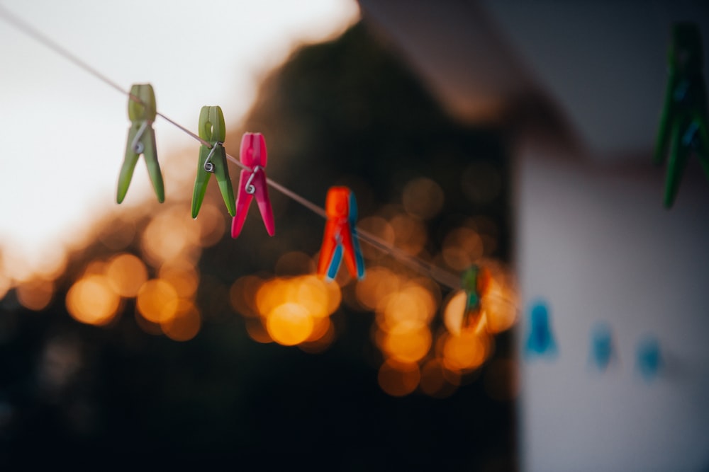 A string of colorful clothes pins hanging from a clothes line