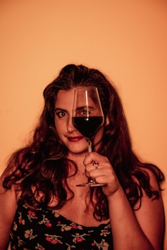 a woman holding a glass of pinot wine in front of her face