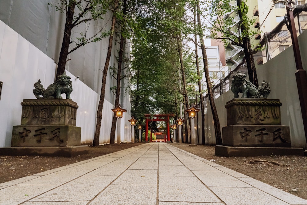 a walkway lined with statues and trees next to a building