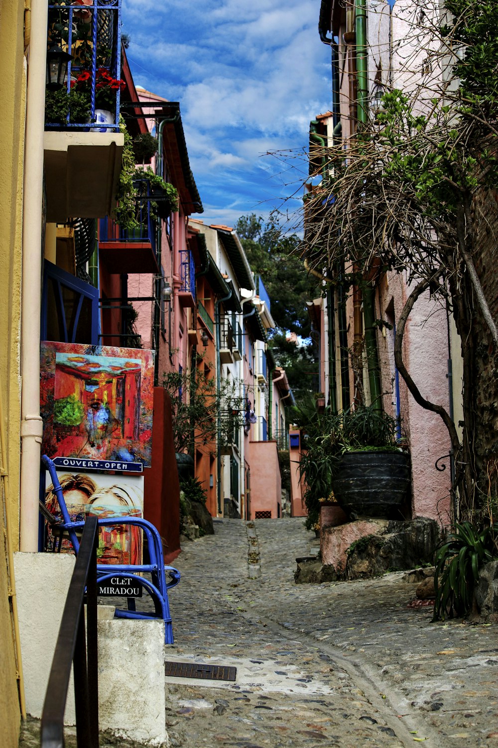 a blue chair sitting in the middle of a cobblestone street