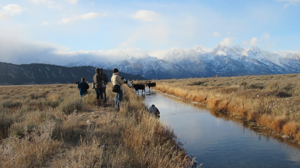 a group of people walking across a grass covered field