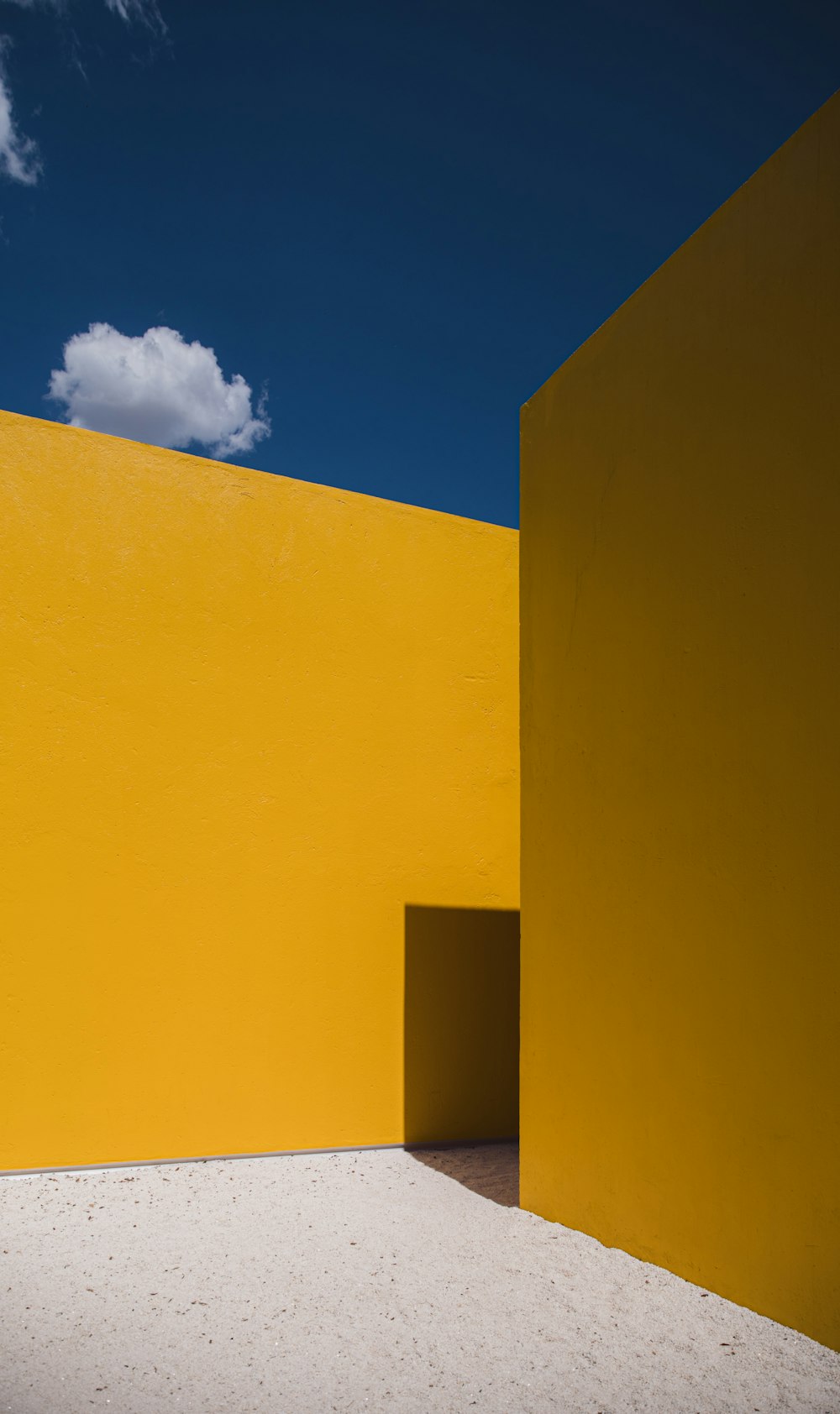 a yellow building with a white floor and a blue sky