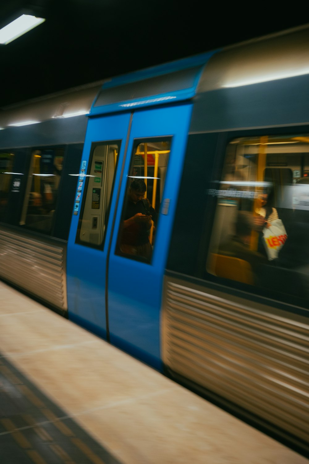 a blue train traveling down train tracks next to a platform