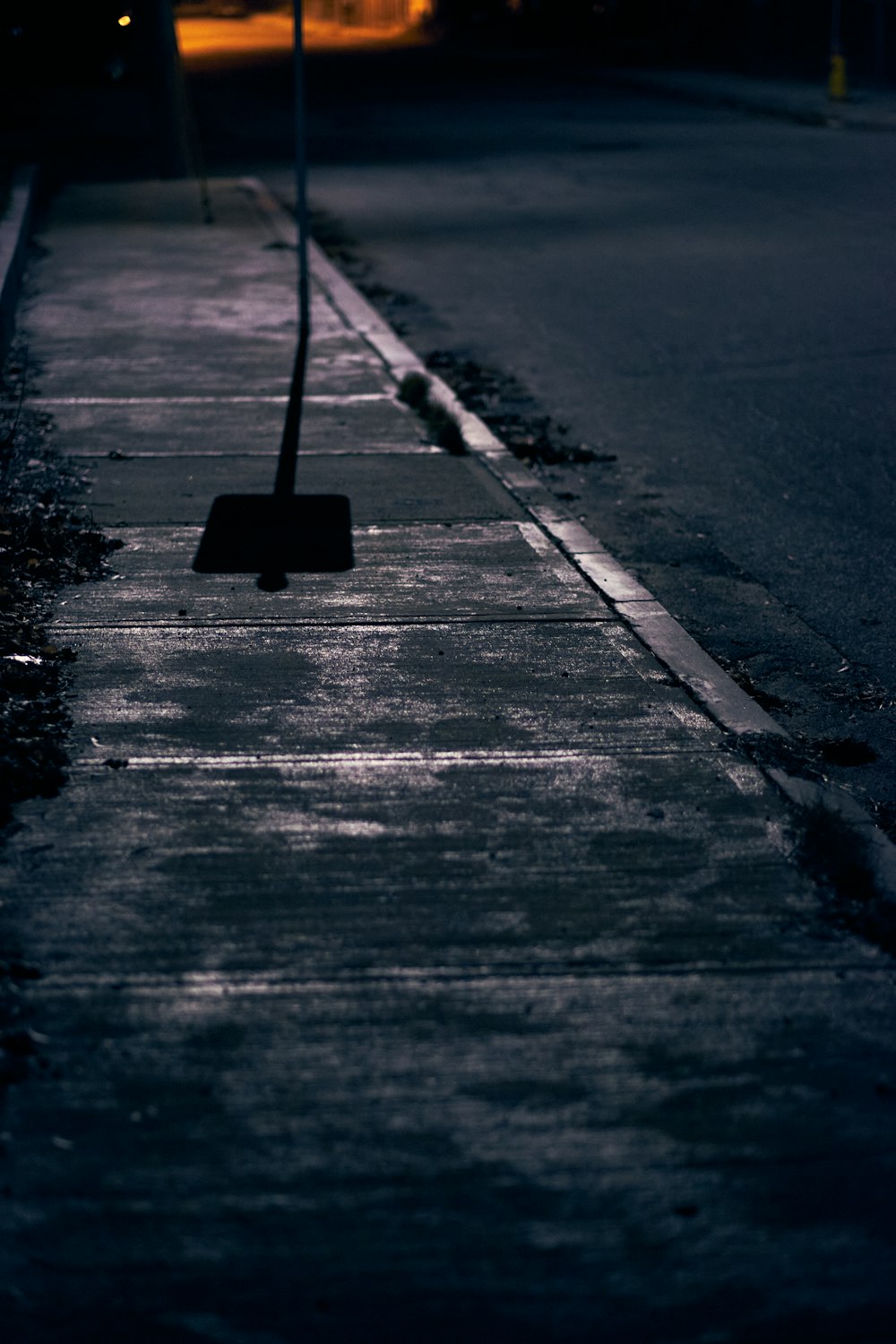 a street sign on a sidewalk at night