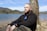 a man sitting next to a tree near a body of water