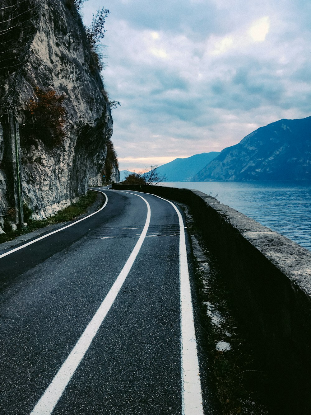 an empty road next to a large body of water