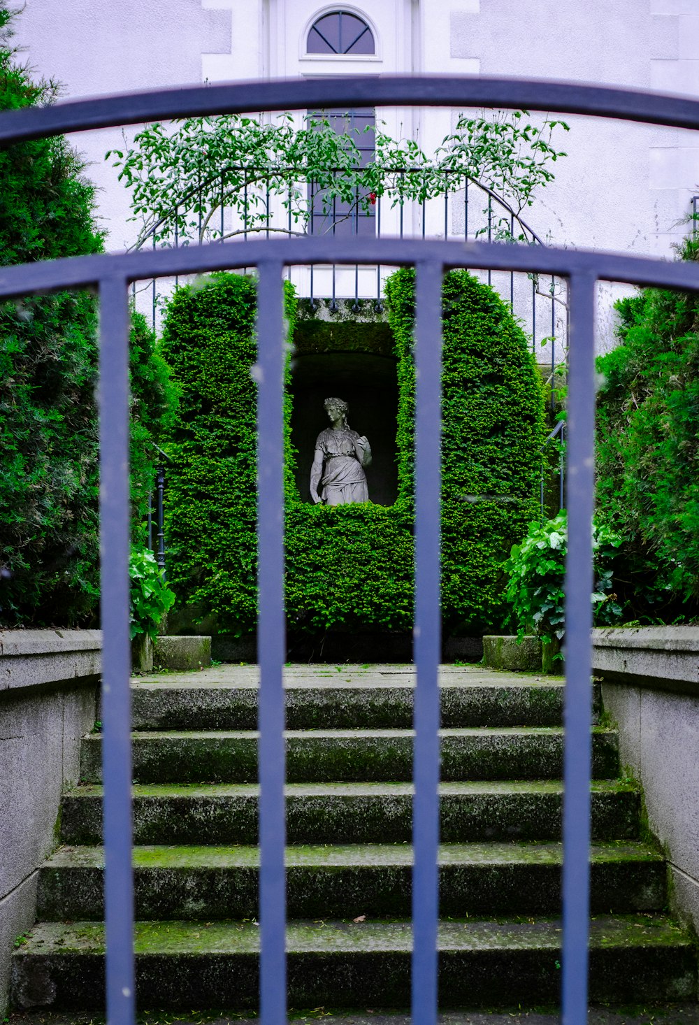 a blue gate with a statue in the middle of it