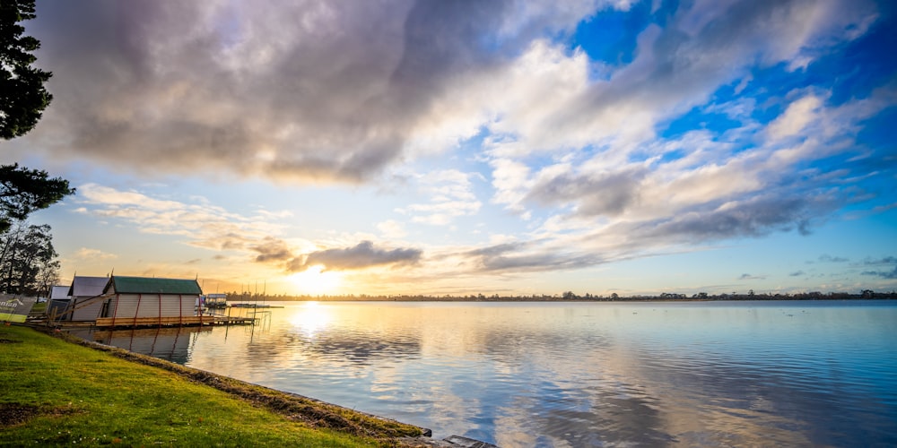 the sun is setting over a lake with a dock