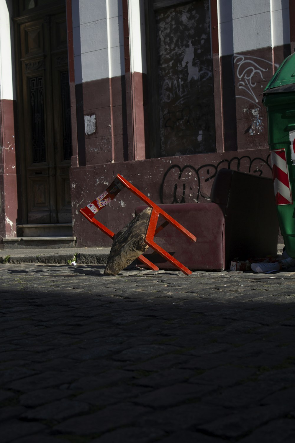 a bird sitting on the ground next to a trash can