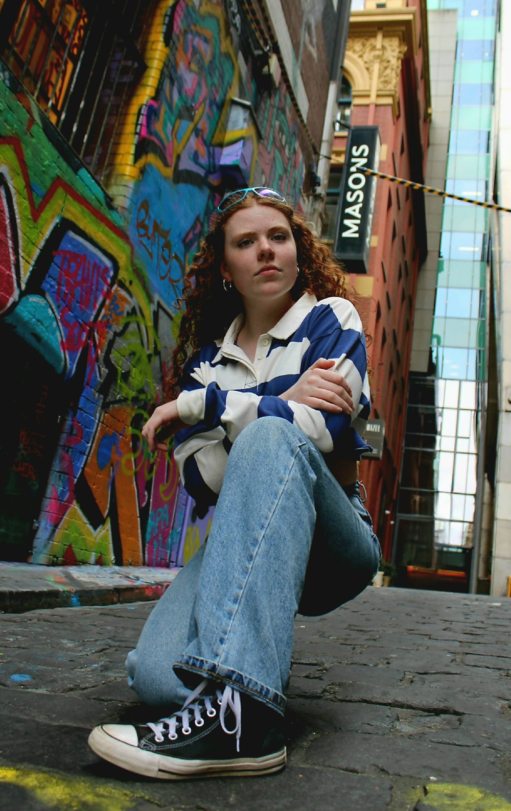 a woman sitting on the ground in front of a building