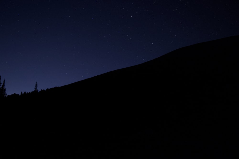 the night sky with stars above a mountain