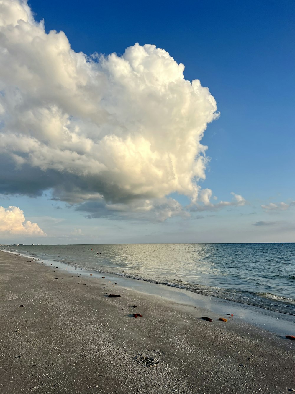 Un ciel nuageux au-dessus de l’océan avec une plage au premier plan