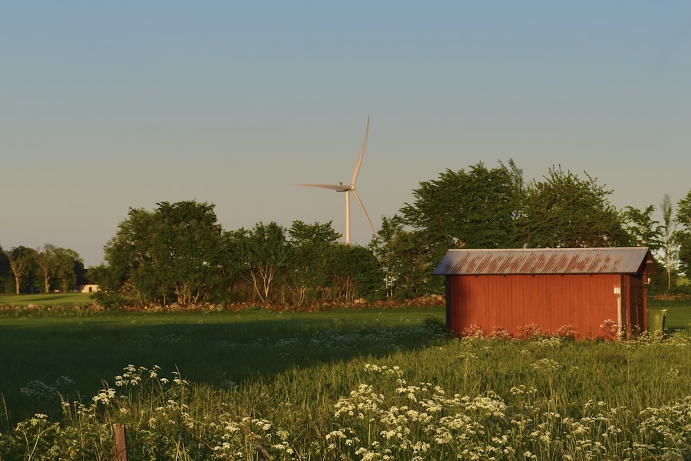 a red shed in a field with a windmill in the background