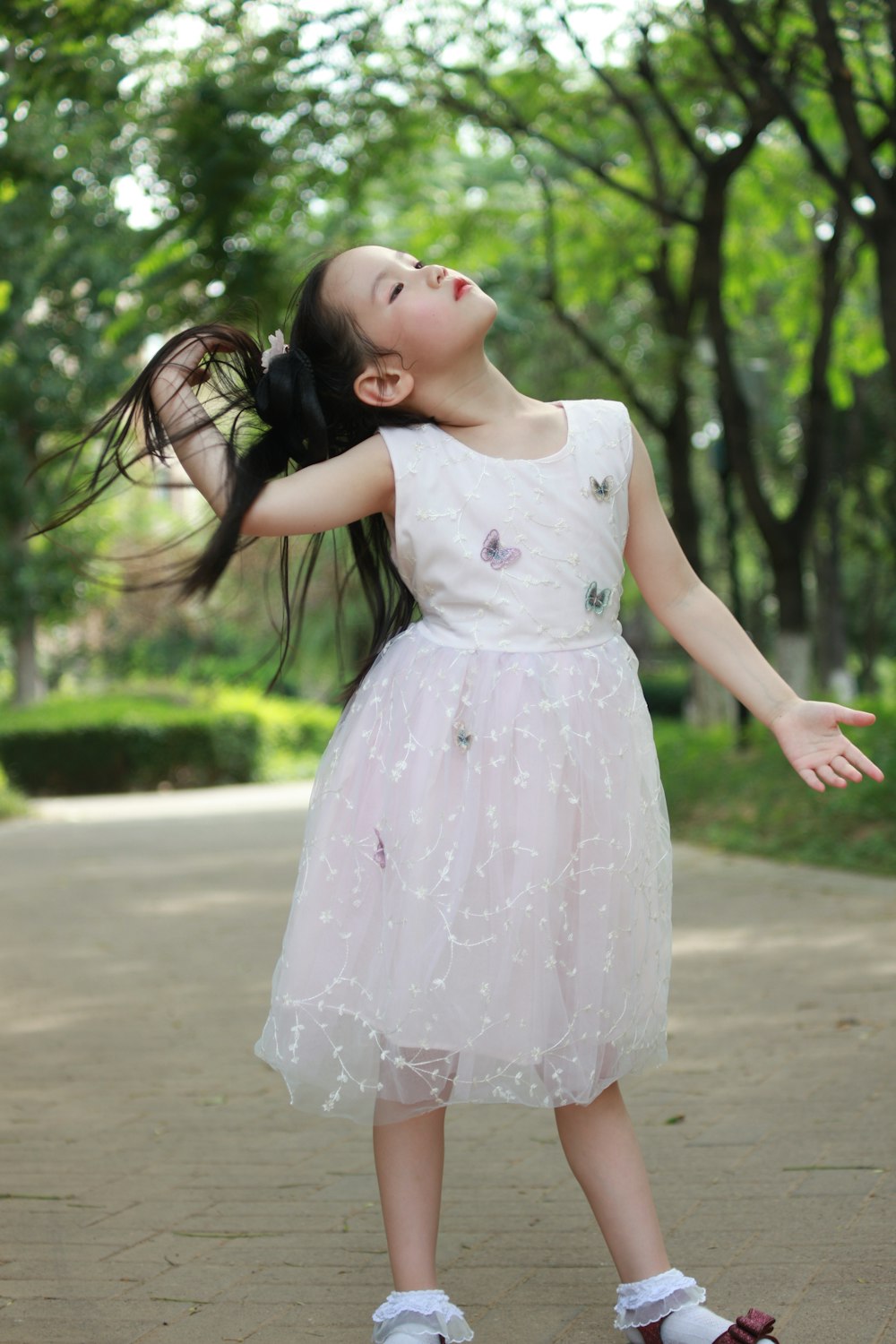 a young girl in a white dress holding her hair