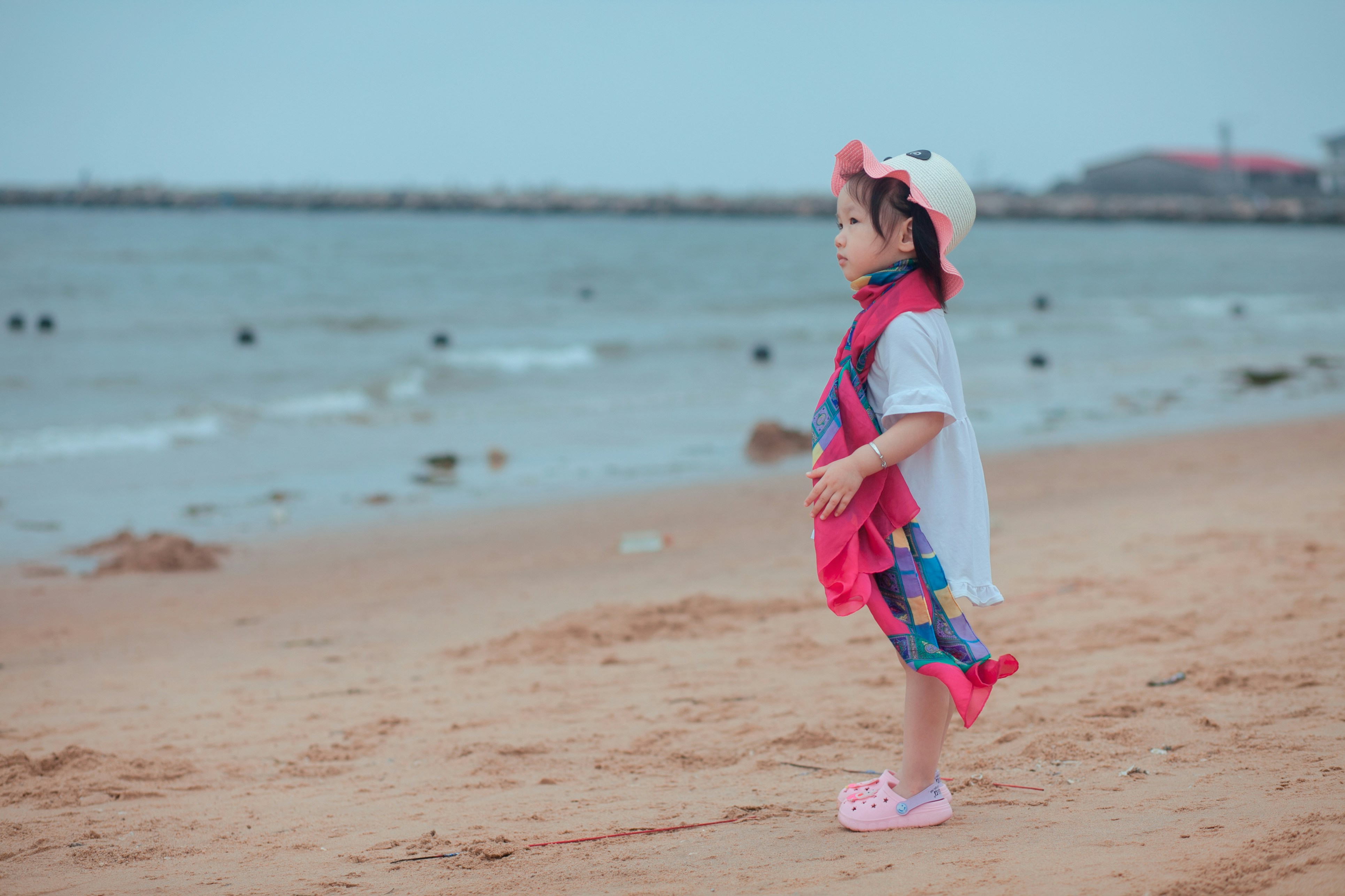a little girl standing on top of a sandy beach