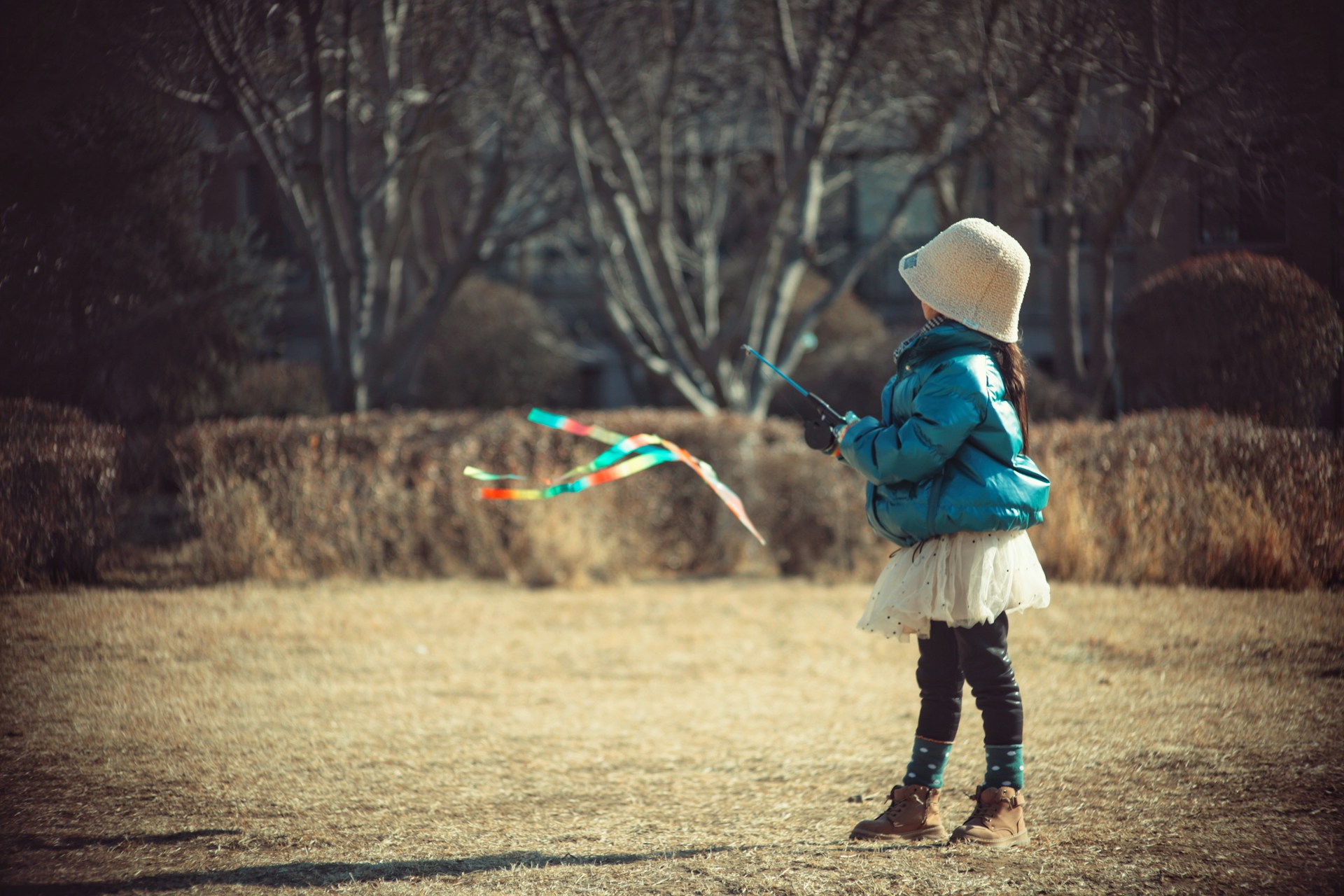 a little girl standing in a field flying a kite