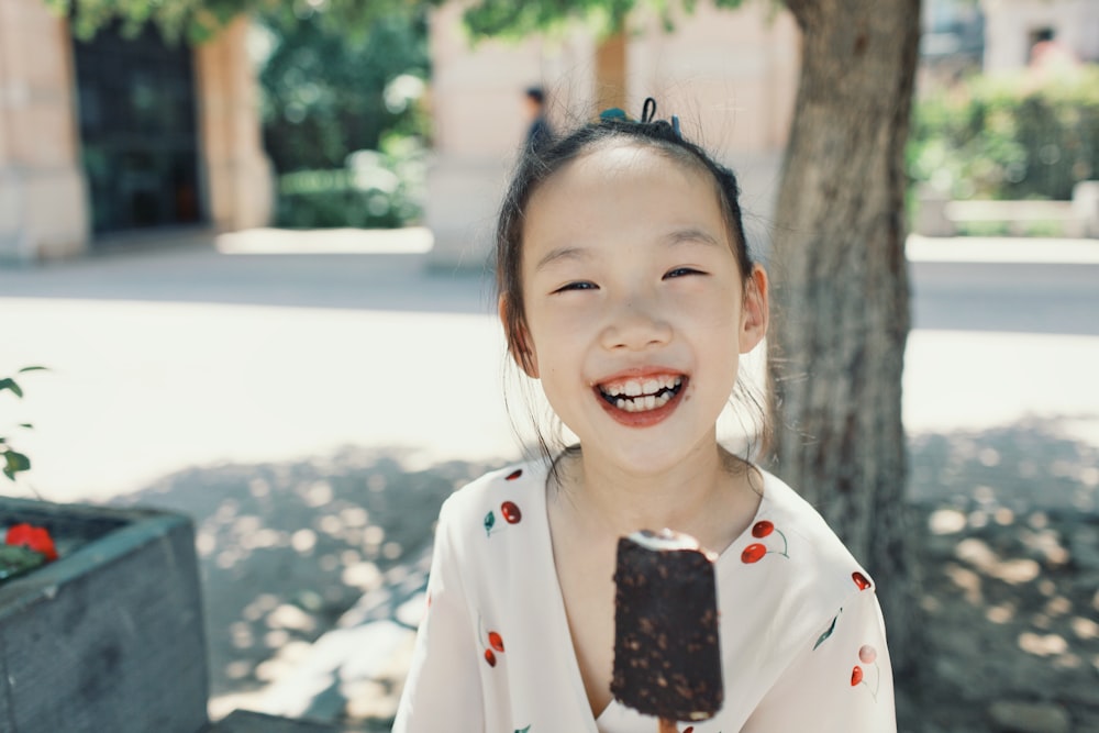 a little girl smiling while holding a piece of chocolate