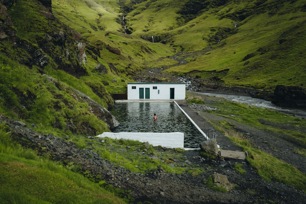 um pequeno edifício branco sentado no topo de uma colina verde exuberante