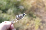 Hands holding a finished jewelry piece with a backdrop of recycled materials.