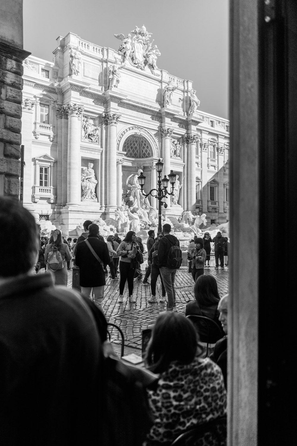 a black and white photo of people walking in front of a building