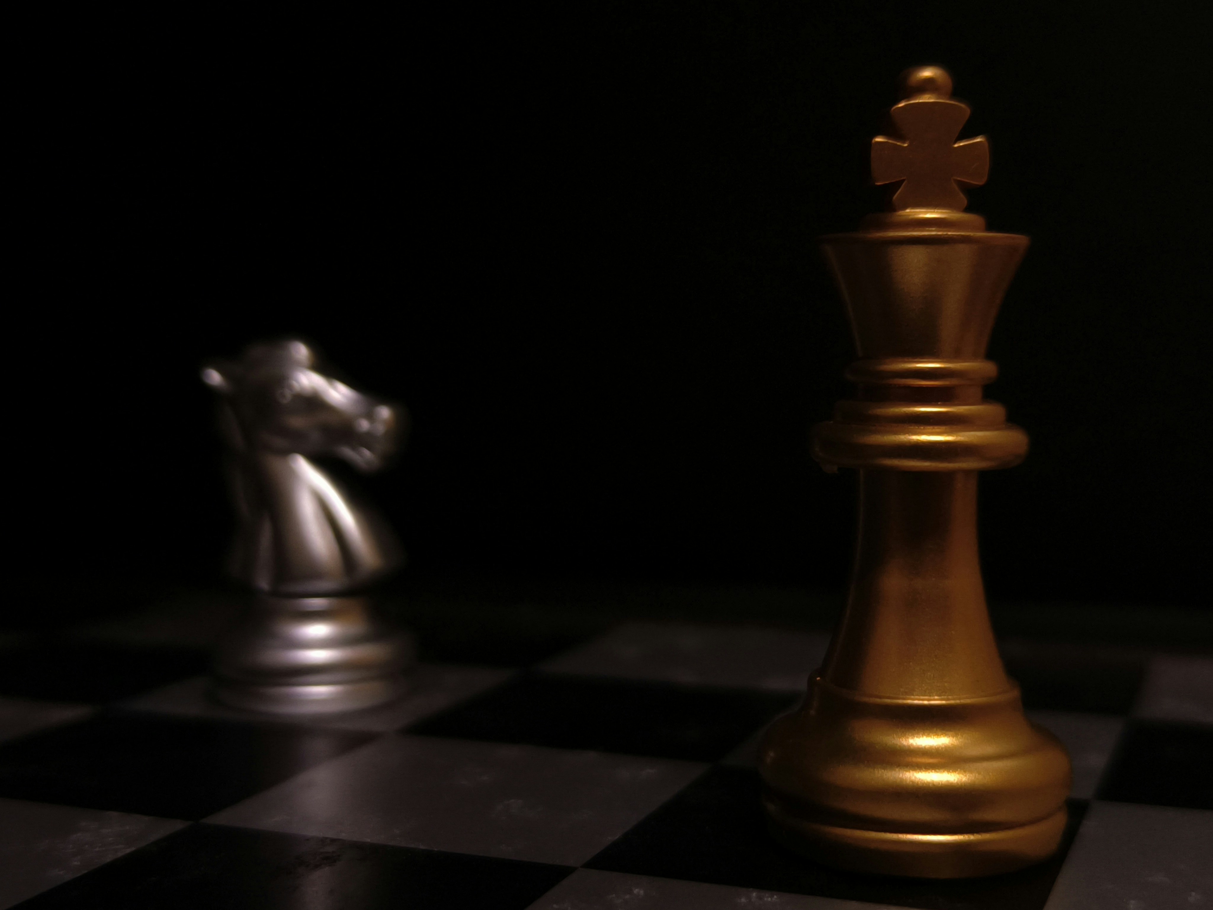 a gold and silver chess piece on a black and white chess board