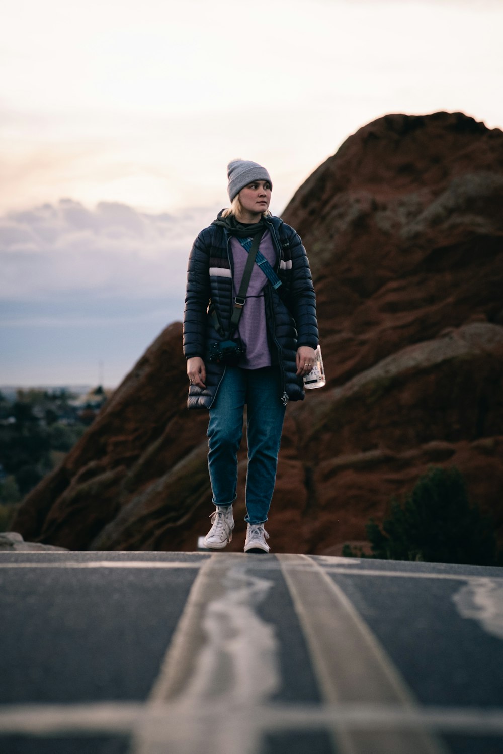 a woman walking down a road with a mountain in the background