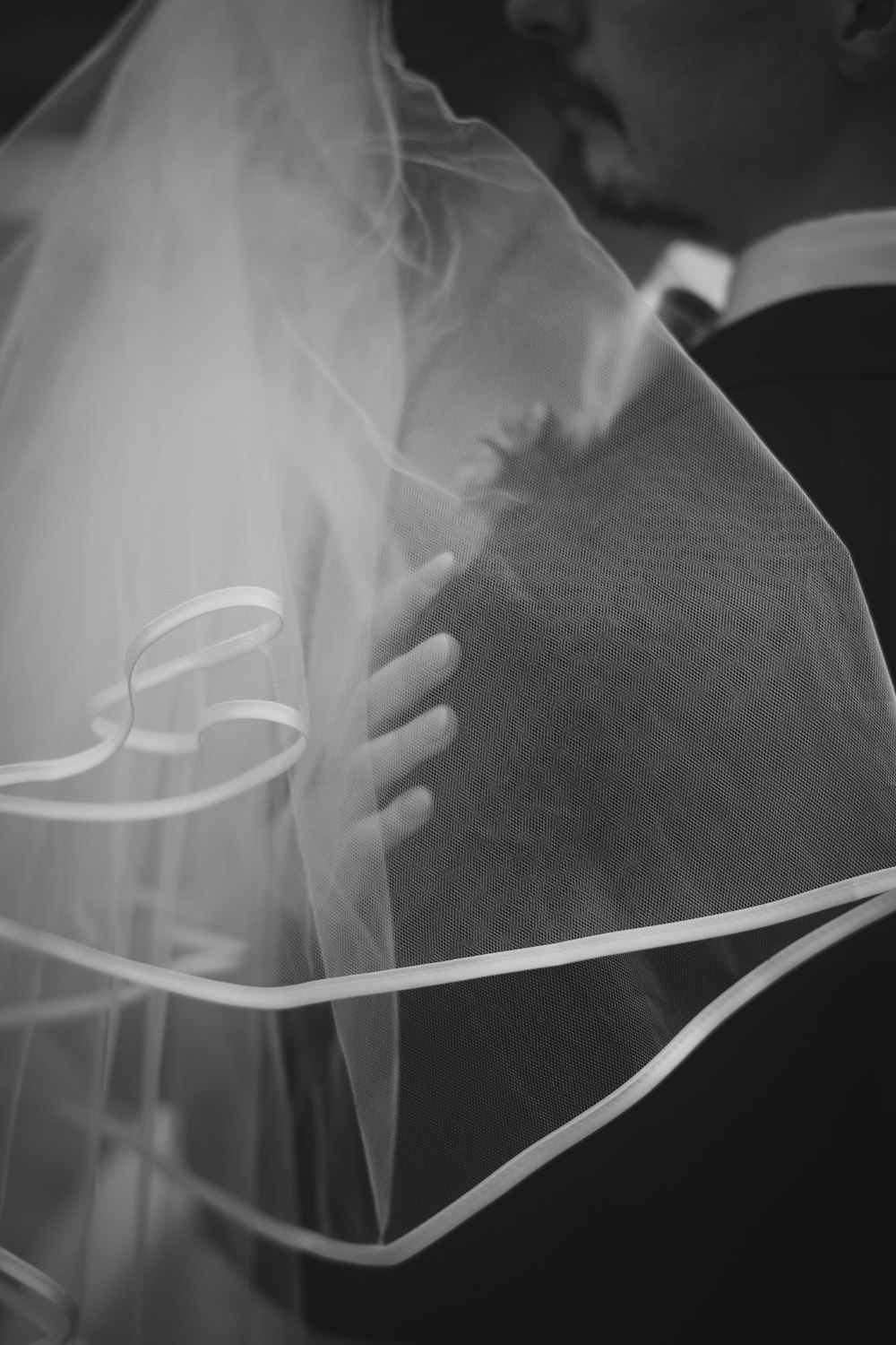 a black and white photo of a bride and groom kissing
