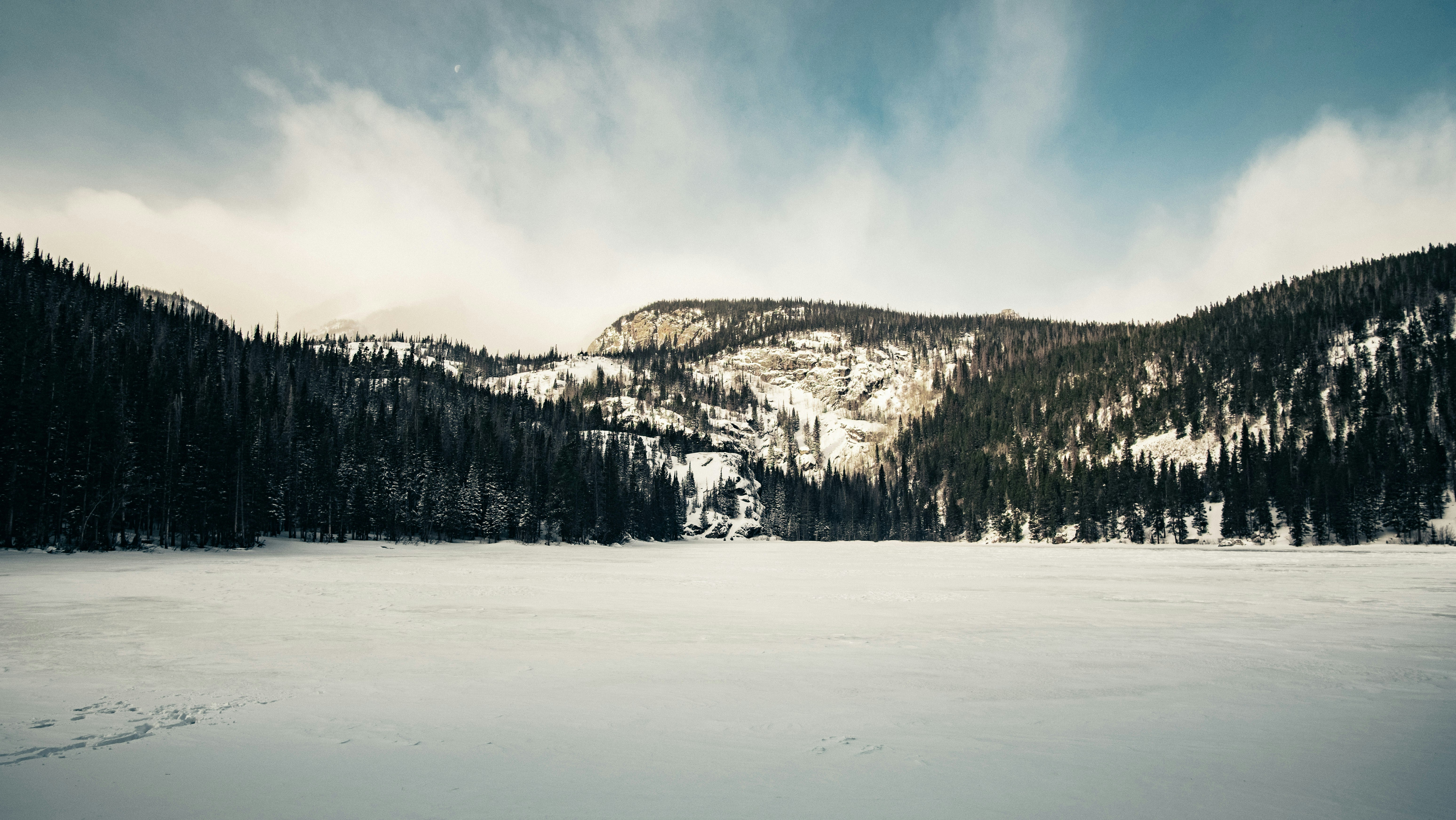 a snow covered field with a mountain in the background