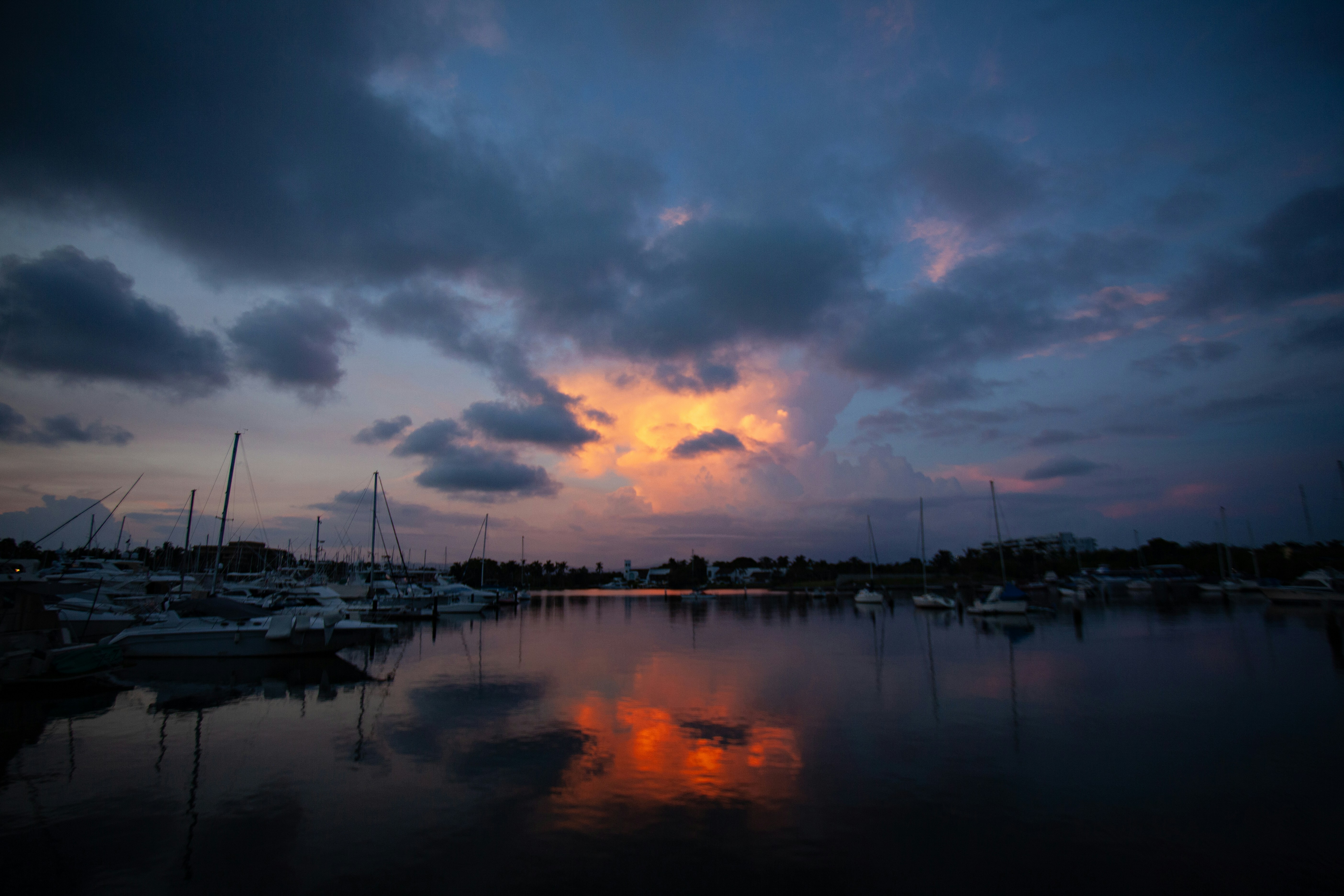 a harbor filled with lots of boats under a cloudy sky, 