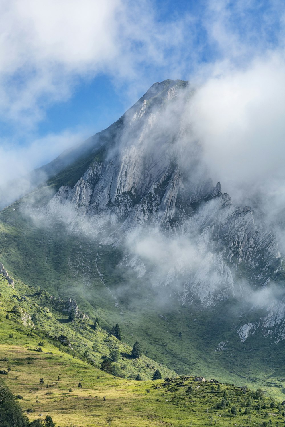 a mountain covered in clouds and green grass