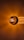 A close-up view of a glowing incandescent light bulb illuminating its surroundings with a warm, amber glow. The light bulb's filaments are visible, creating a bright and radiant center that gradually fades into darker tones at the edges.