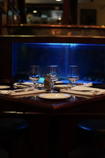 An intimate dining table bathed in warm ambient lighting with sleek black and navy decor.