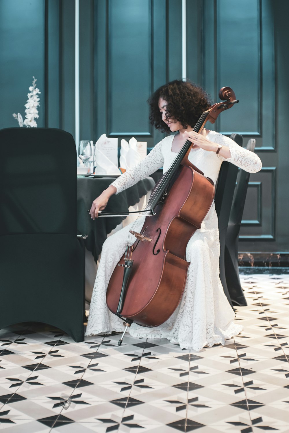 a woman in a white dress playing a cello