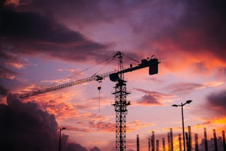 Sunset silhouette of a crane towering over a developing urban area in Saudi Arabia.