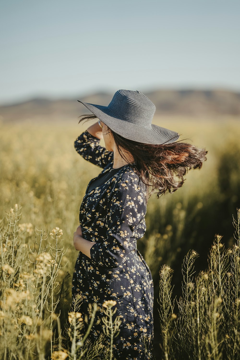 a woman wearing a hat standing in a field