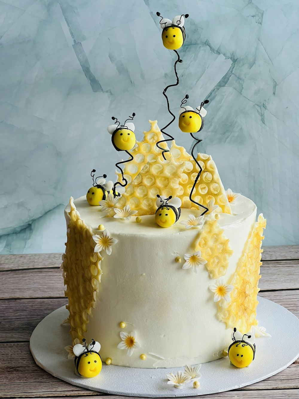 Un pastel decorado con abejas y margaritas en un plato