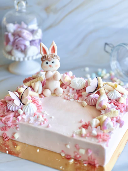 A pastel delicately decorated with pink and mint green frosting, surrounded by soft pastel decorations.