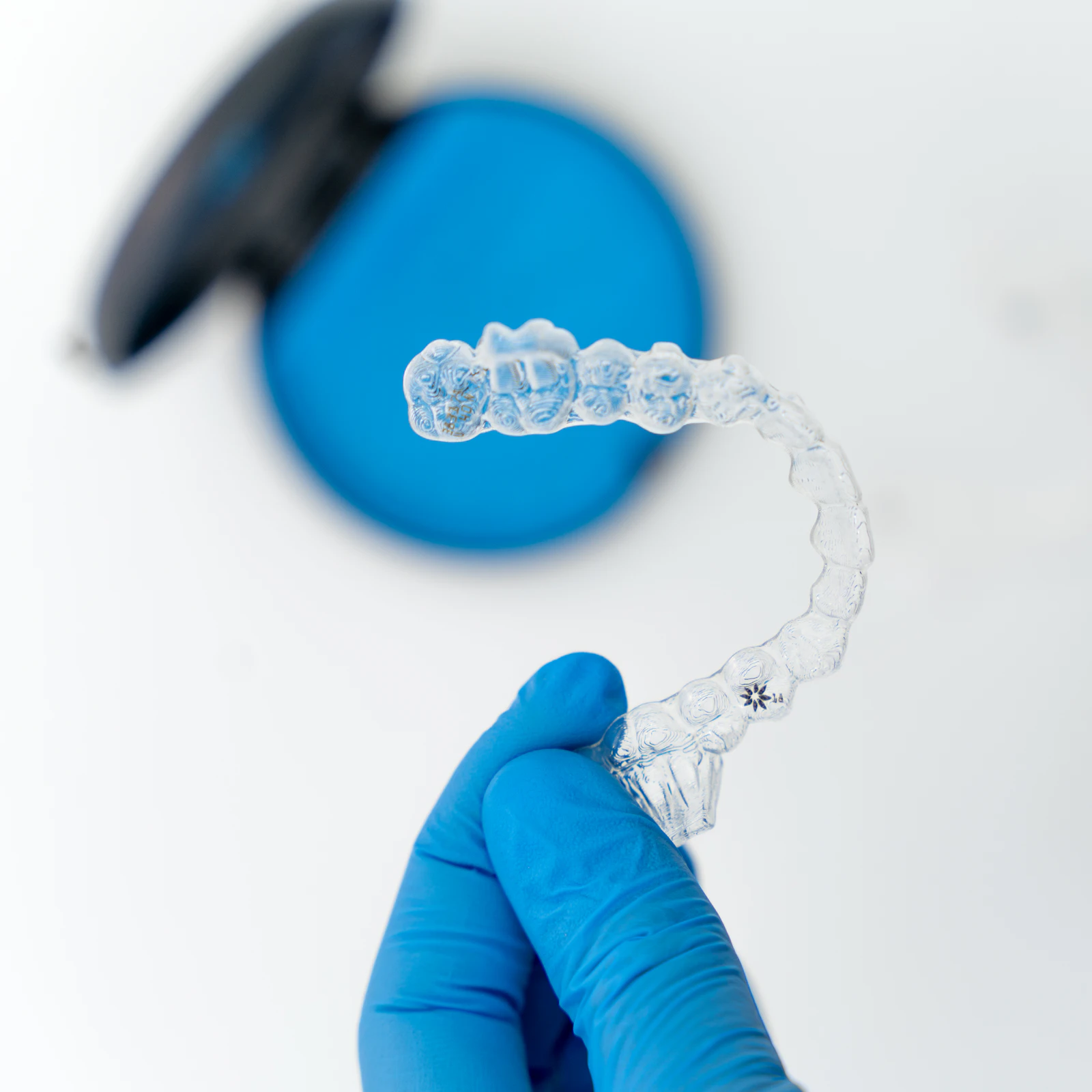 A gloved hand holding a clear orthodontic aligner tray