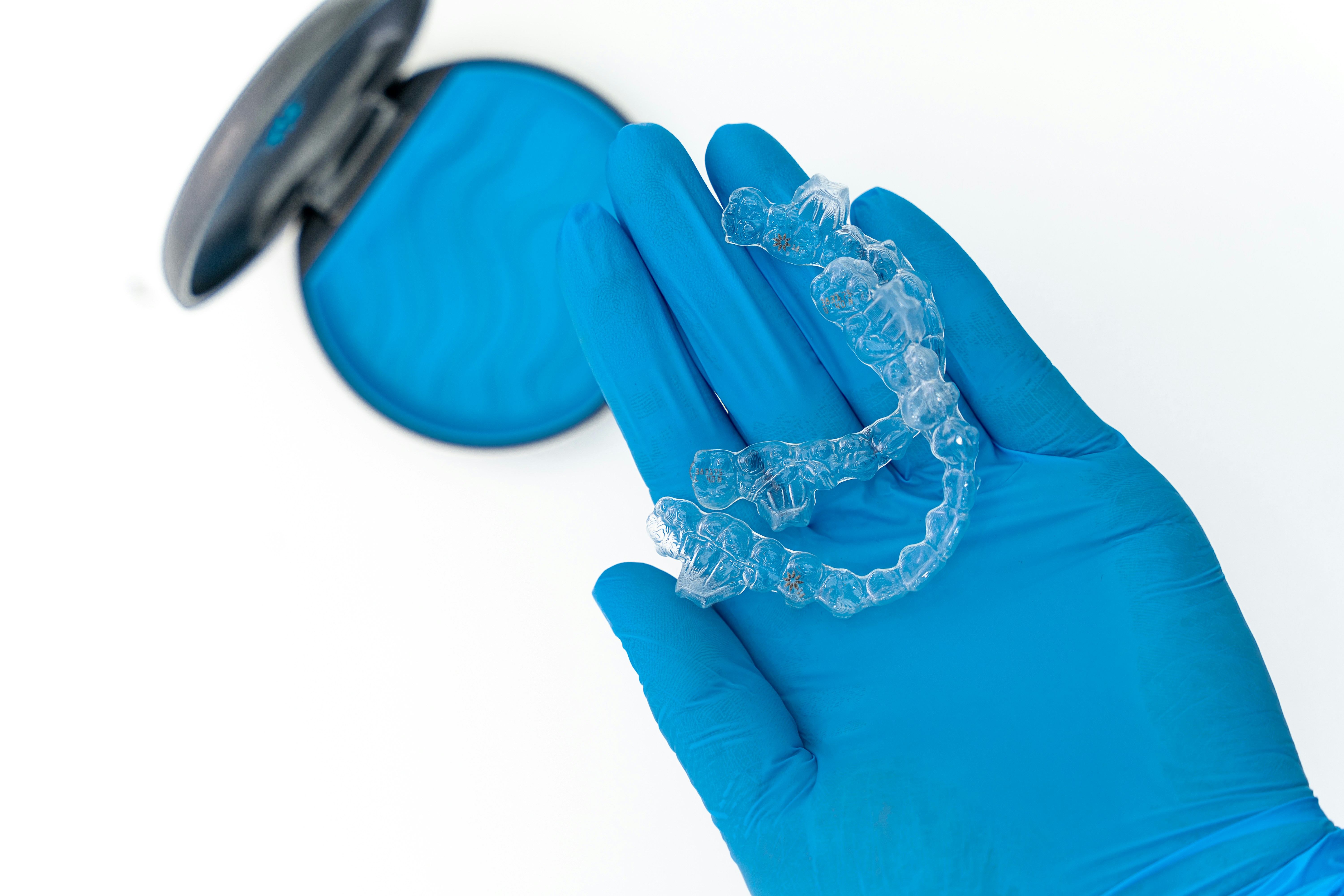 a person in blue gloves holding a toothbrush