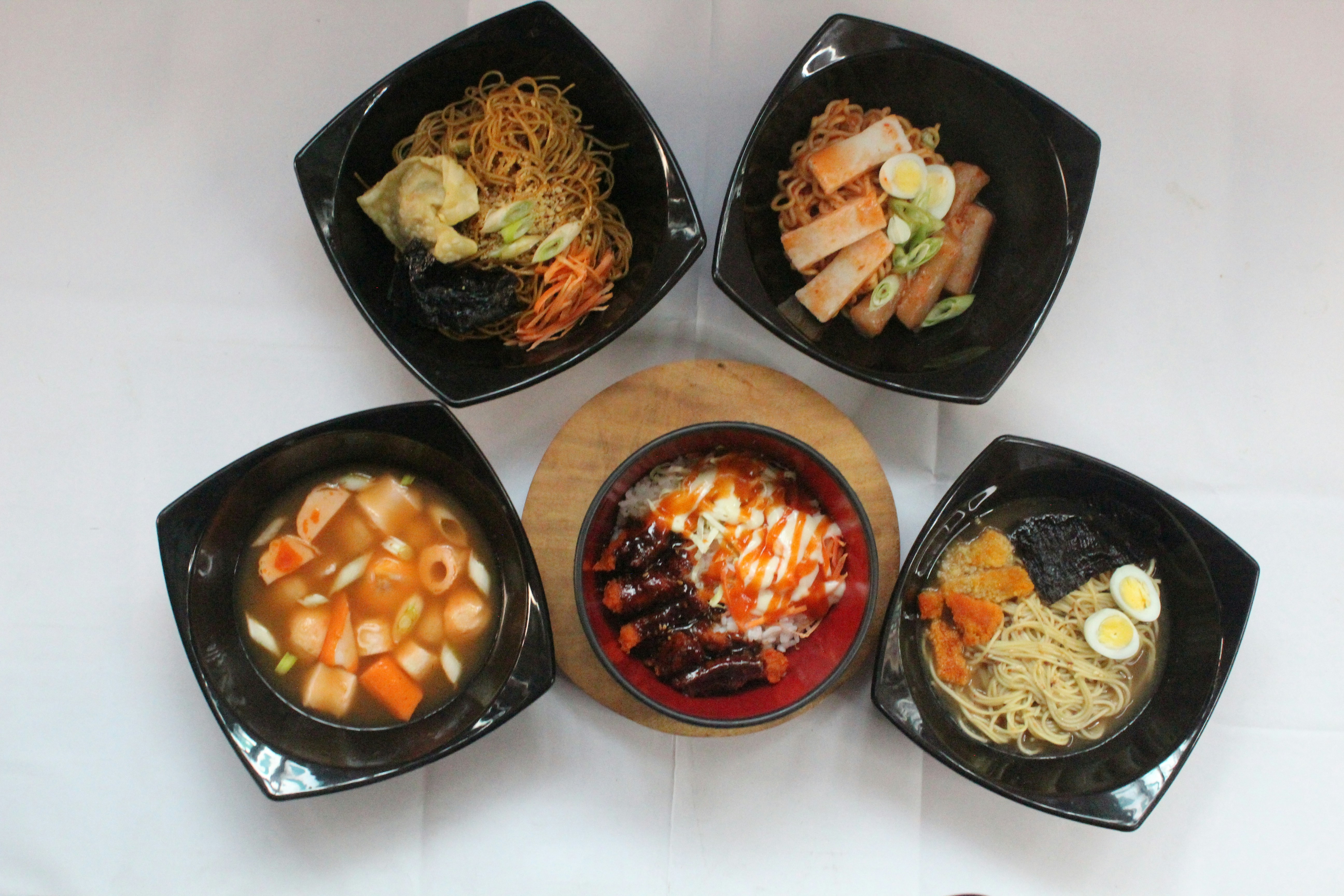 a table topped with four black bowls filled with food