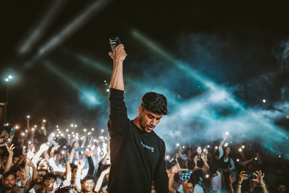 a man standing in front of a crowd holding a cell phone