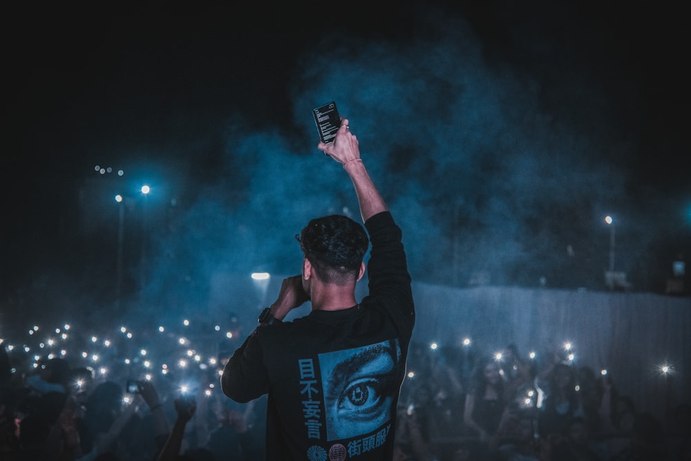 a man holding a cell phone up in the air