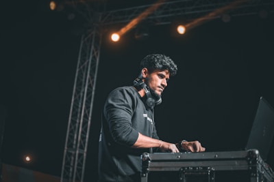 DJ Kiko wearing headphones, focused on the playlist on a laptop screen.